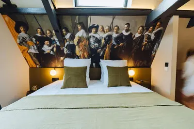 a bedroom with a large bed with a painting on the wall at Løk Historics luxury art-inspired loft in historic city centre! in Haarlem