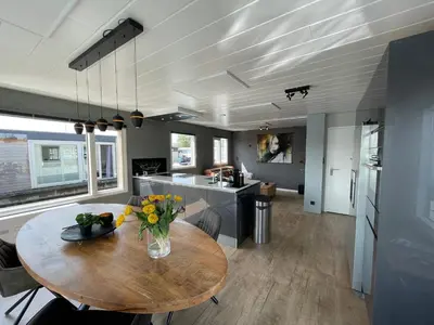 a kitchen and dining room with a wooden table at Poellodge XL, houseboat met whirlpool en sauna in Aalsmeer