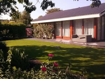 a house with a green yard with a bench at Enjoyable holiday home in Noordwijk