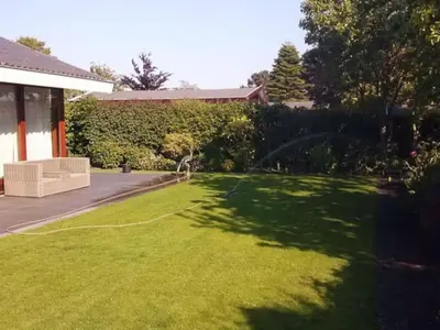 a yard with a large green lawn with a house at Enjoyable holiday home in Noordwijk