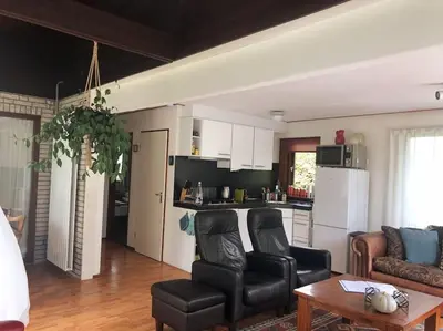 a living room with two chairs and a kitchen at Enjoyable holiday home in Noordwijk
