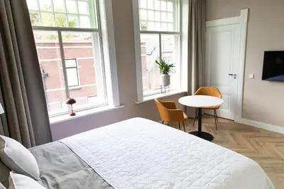 a bedroom with a bed and a table and two windows at Boutique Pastorale in Linschoten