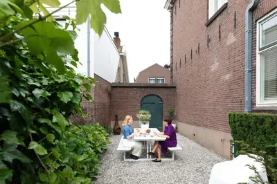two women sitting at a table in a courtyard at Boutique Pastorale in Linschoten