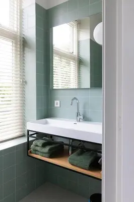 a bathroom with a sink and a mirror and green tiles at Boutique Pastorale in Linschoten