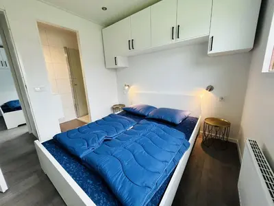a bed with blue pillows in a white room at Bungalowpark de Horn - Floresta 213 in Dirkshorn