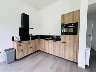 a kitchen with wooden cabinets and a tv on a wall at Bungalowpark de Horn - Floresta 213 in Dirkshorn