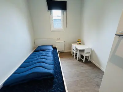 a small bedroom with a blue bed and a table at Bungalowpark de Horn - Floresta 213 in Dirkshorn
