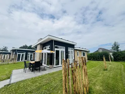 a tiny house with a table and chairs in a yard at Bungalowpark de Horn - Floresta 213 in Dirkshorn