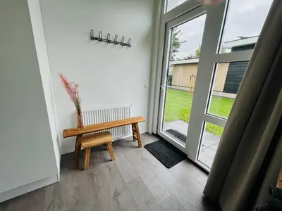 a wooden bench in a room with a sliding glass door at Bungalowpark de Horn - Floresta 214 in Dirkshorn