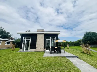 a small house with a table and chairs in the yard at Bungalowpark de Horn - Floresta 214 in Dirkshorn