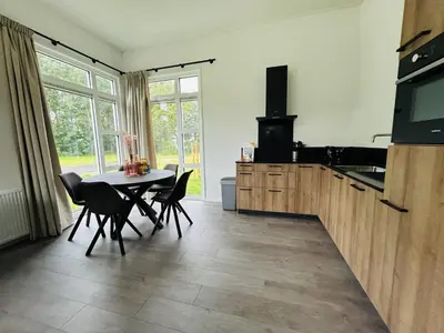 a kitchen with a table and chairs and a television at Bungalowpark de Horn - Floresta 215 in Dirkshorn