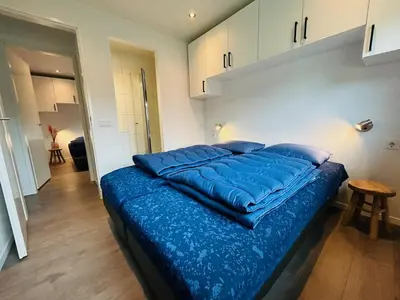 a bed with a blue comforter in a bedroom at Bungalowpark de Horn - Floresta 215 in Dirkshorn