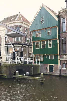 a green building next to a river with buildings at Huis met de Kogel in Alkmaar