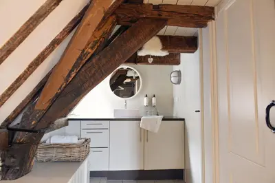 a kitchen with white cabinets and wooden beams at Huis met de Kogel in Alkmaar