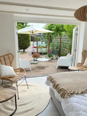 a bedroom with a bed and chairs and a patio at Tranquil Guest House in Zandvoort