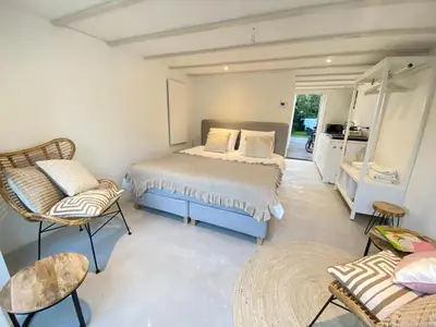 a bedroom with a bed and chairs in a room at Tranquil Guest House in Zandvoort
