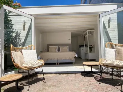 a bedroom with a bed and two chairs on a patio at Tranquil Guest House in Zandvoort
