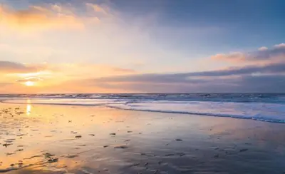 a sunset on a beach with the ocean at Tranquil Guest House in Zandvoort