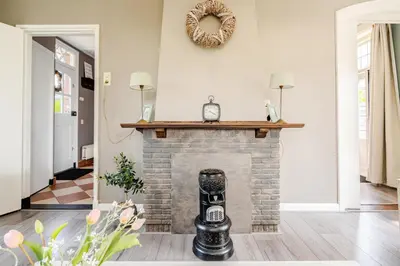 a living room with a brick fireplace with a clock on it at Gastenverblijf in het voorhuis van onze woonboerderij in Maartensdijk