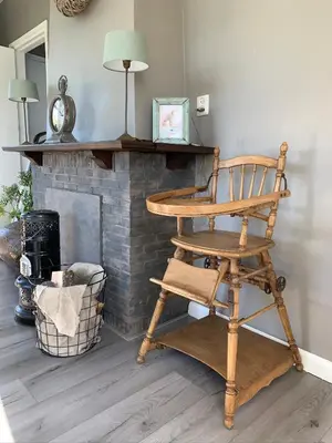 a wooden chair sitting in front of a fireplace at Gastenverblijf in het voorhuis van onze woonboerderij in Maartensdijk