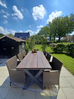 a wooden table with wicker chairs around it at Gastenverblijf in het voorhuis van onze woonboerderij in Maartensdijk