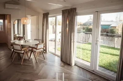 a dining room with a table and chairs and large windows at Waterfront tiny home with spacious garden in Vinkeveen