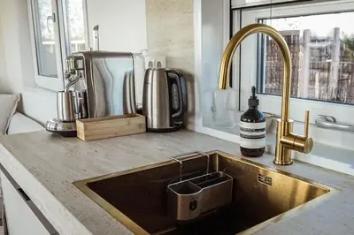 a kitchen counter with a sink with a bottle of wine at Waterfront tiny home with spacious garden in Vinkeveen