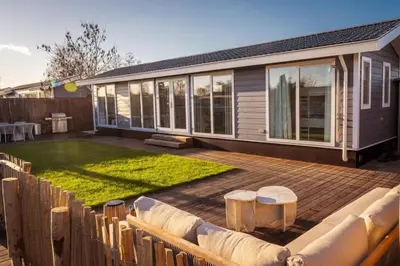 a backyard with a wooden deck with a lawn at Waterfront tiny home with spacious garden in Vinkeveen