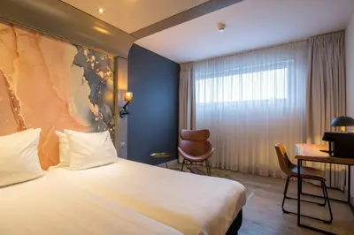 a hotel room with a bed and a desk at Leonardo Hotel Almere City Center in Almere