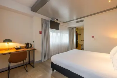 a hotel room with a bed and a desk with a chair at Leonardo Hotel Almere City Center in Almere