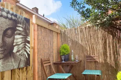 a fence with two chairs and a table with a picture of a head at Beach House Sea La Vie 50 meters from the beach in Zandvoort