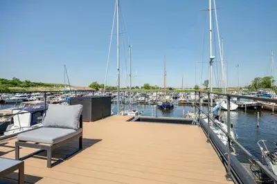 a chair on a dock with boats in a marina at Moderne houseboat op het water! in Assendelft