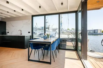 a kitchen with a table and blue chairs in a house at Moderne houseboat op het water! in Assendelft