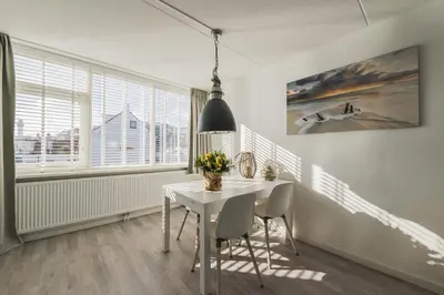 a white dining room with a white table and chairs at Strand 122 Appartement in Egmond aan Zee