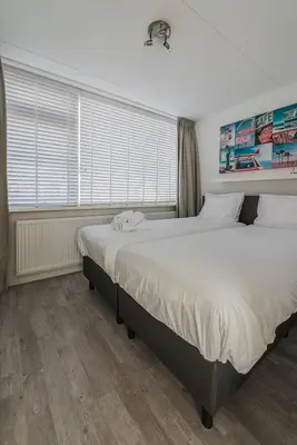 a bedroom with two beds and a window at Strand 122 Appartement in Egmond aan Zee