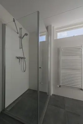 a bathroom with a shower with a glass door at Strand 122 Appartement in Egmond aan Zee