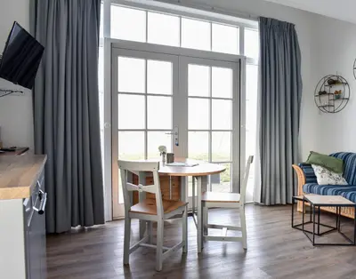 a living room with a table and chairs and a window at Pronkhuisje in Oterleek