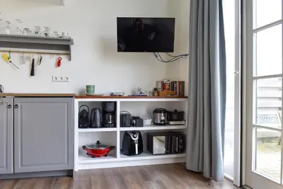 a kitchen with a white shelving unit at Pronkhuisje in Oterleek