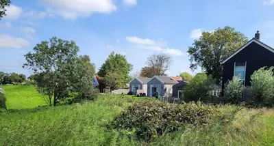 a house in a grassy field with a house at Pronkhuisje in Oterleek