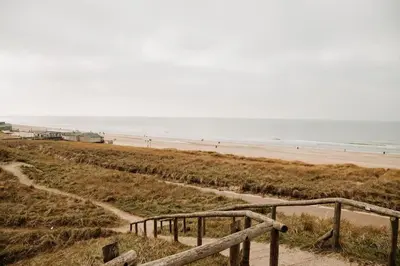 a stairway to the beach with people walking on the beach at Etoile31 seaside apartment Egmond aan Zee in Egmond aan Zee
