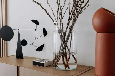 a vase with branches in it on a table at Etoile31 seaside apartment Egmond aan Zee in Egmond aan Zee