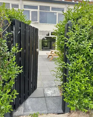 a black fence with bushes in front of a building at Eight in Zandvoort