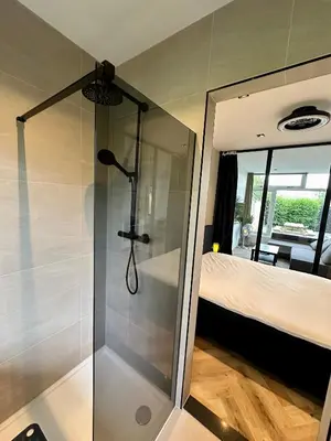 a shower with a glass door in a bedroom at Eight in Zandvoort