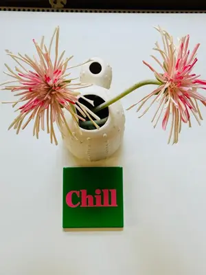 a vase with flowers in it next to a sign at Cosy summerhouse in Noordwijk aan Zee