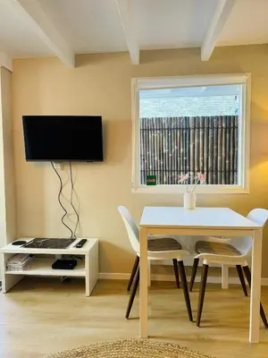 a living room with a table and a tv at Cosy summerhouse in Noordwijk aan Zee