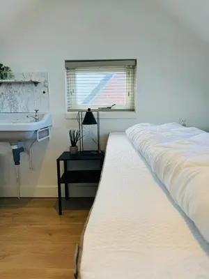 a bedroom with a large bed and a sink at Zomerhuis - Gratis parkeren! in Noordwijk aan Zee