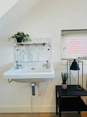 a bathroom with a white sink and a mirror at Zomerhuis - Gratis parkeren! in Noordwijk aan Zee