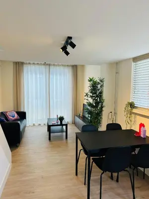 a living room with a black table and chairs at Zomerhuis - Gratis parkeren! in Noordwijk aan Zee