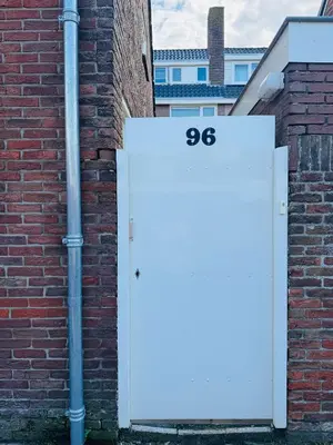 a white door with the number on a brick wall at Zomerhuis - Gratis parkeren! in Noordwijk aan Zee