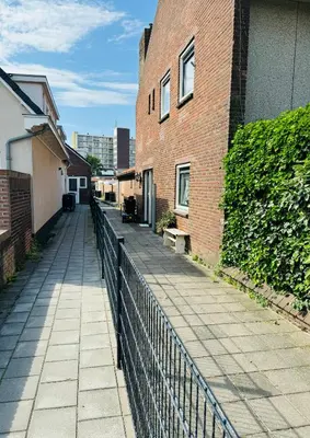 a sidewalk next to a brick building with a fence at Zomerhuis - Gratis parkeren! in Noordwijk aan Zee
